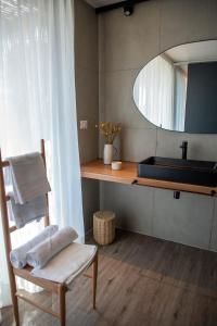 a bathroom with a sink and a chair and a mirror at Vibo Wine Lodge At Viu Manent in Santa Cruz