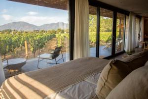 a bedroom with a bed and a view of a vineyard at Vibo Wine Lodge At Viu Manent in Santa Cruz