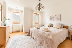 a white bedroom with a large bed and two windows at Villa Venus in Willendorf in der Wachau