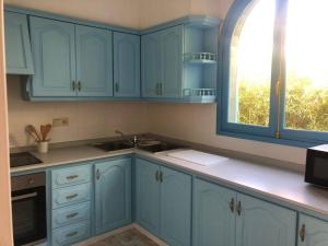 a kitchen with blue cabinets and a window at Villa Azul Beach in Piles