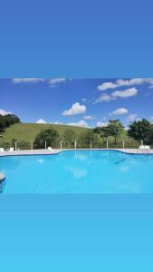 a large blue swimming pool with a hill in the background at Pousada Vida feliz in Águas de Lindoia