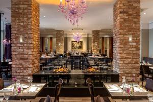 a restaurant with tables and chairs and a chandelier at Dorint Kongresshotel Düsseldorf/Neuss in Neuss