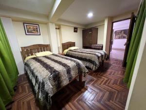2 camas en una habitación con cortinas verdes en Euro Hostal, en Cusco