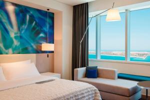 a hotel room with a bed and a chair and a window at Le Royal Meridien Abu Dhabi in Abu Dhabi