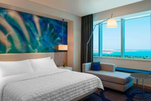 a bedroom with a bed and a chair and a large window at Le Royal Meridien Abu Dhabi in Abu Dhabi