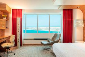 a bedroom with a bed and a desk and a window at Le Royal Meridien Abu Dhabi in Abu Dhabi