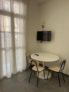a white table and chairs in a room with a tv at CasaCalzolari FIERA METEO TECNOPOLO BO in Bologna