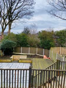um jardim com uma cerca de madeira e bancos em Warm welcoming Home em Manchester