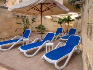 eine Gruppe Stühle und ein Sonnenschirm auf einer Terrasse in der Unterkunft Sunny Villa in Nadur