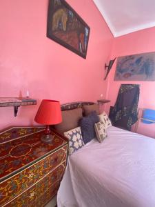 a bedroom with pink walls and a bed with a red lamp at Dar Sam - Red Room in Rabat