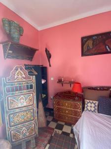 a bedroom with pink walls and a bed and a dresser at Dar Sam - Red Room in Rabat