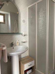 a white bathroom with a sink and a shower at La Perla di Lampedusa in Lampedusa