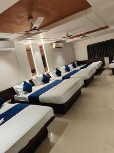 a row of beds in a room with blue pillows at Hotel Anand Palace in Shirdi