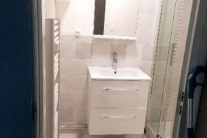 une salle de bain blanche avec un lavabo et un miroir dans l'établissement Studio bord de mer, à Courseulles-sur-Mer 25 autres photos