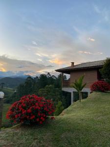 una casa en la cima de una colina con flores rojas en Pousada Chales Joao de Barro, en Visconde De Maua