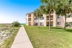 a building on the beach with palm trees and a sidewalk at Sunset Harbor Palms 2-304 in Navarre