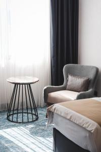 a room with a bed and a chair and a table at Bristol Hotel Podgorica in Podgorica