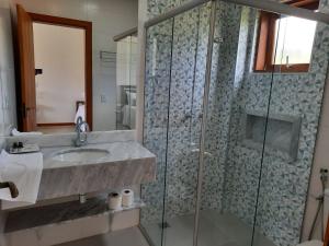 a bathroom with a sink and a glass shower at Pousada Cheiro da Terra in Capitólio