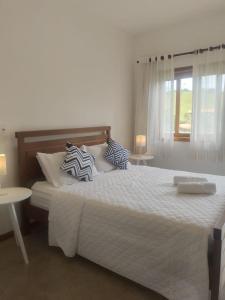 a bedroom with a large white bed with pillows on it at Pousada Cheiro da Terra in Capitólio