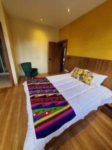 Un dormitorio con una cama grande con una manta de colores. en Hotel Inti Quito, en Quito