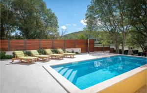 a swimming pool with lounge chairs and a fence at Stunning Home In Dicmo With Kitchen in Dicmo