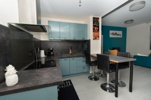 a kitchen with blue cabinets and a table with chairs at Le Paradis Bleu in Lourdes