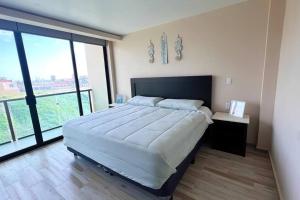 um quarto com uma cama grande e janelas grandes em Luxury 2BR Condo Rosarito (D) em Rosarito