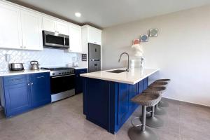 uma cozinha com armários azuis e um lavatório e dois bancos em Luxury 2BR Condo Rosarito (D) em Rosarito