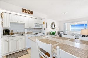 a kitchen and dining room with white cabinets and a table at Sunset Harbor Palms 1-308 in Navarre