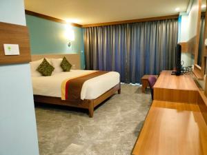 Habitación de hotel con cama y TV en Saisawan Beach Resort, en Na Jomtien