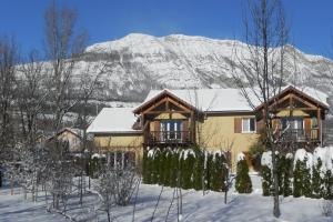 una casa nella neve con una montagna sullo sfondo di À la Petite Maison a Gap