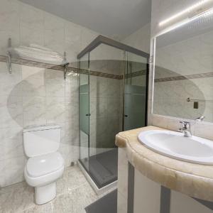 a bathroom with a toilet and a sink and a shower at Hotel Kokusai in Cochabamba