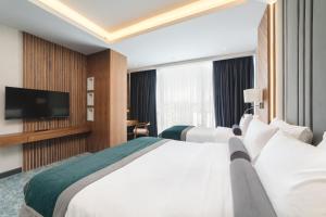 a hotel room with two beds and a flat screen tv at Bristol Hotel Podgorica in Podgorica