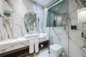 a marble bathroom with a sink and a shower at Bristol Hotel Podgorica in Podgorica