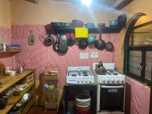 cocina con fogones, ollas y sartenes en la pared en Casa de los colores San cris, en San Cristóbal de Las Casas