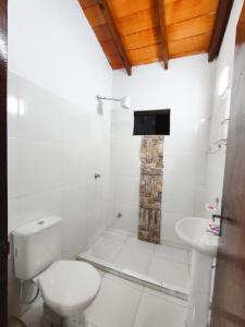 a white bathroom with a toilet and a sink at Las Salinas Hostal in Luque