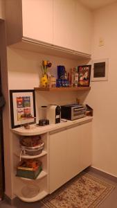 una pequeña cocina con armarios blancos y microondas en Cantinho familiar-Humaitá - somente mulheres - just women, en Río de Janeiro