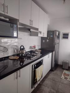 La cuisine est équipée de placards blancs et d'un four avec plaques de cuisson. dans l'établissement Apartment 4 Rent - Av. San Borja Norte Cdra 7, à Lima