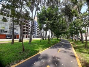 a tree lined path in a park with a building at Apartment 4 Rent - Av. San Borja Norte Cdra 7 in Lima