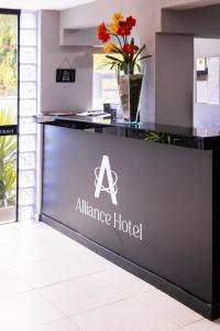 un cartel en un hotel de la alianza con flores en el mostrador en Alliance Hotel, en Bauru