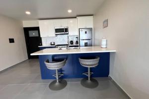 a kitchen with a blue island with two bar stools at Luxury 2BR Condo (F) Rosarito in Rosarito