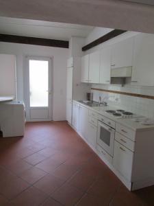 a kitchen with white cabinets and a red tile floor at Casa Sott Al Sass in Ascona
