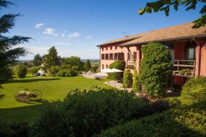 a house with a grass yard next to a building at Agriturismo Casa Rossa Ai Colli in Ragogna