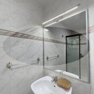 a white bathroom with a sink and a mirror at Hotel Kokusai in Cochabamba