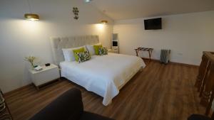 1 dormitorio con 1 cama blanca y TV en Adamas House Hotel Boutique, en Quito