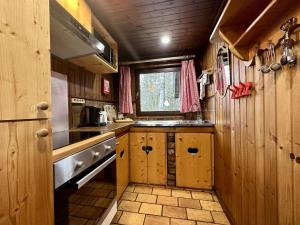 cocina con armarios de madera, fregadero y ventana en Rustic Chalet ultimate relaxation in the forest, en Sourbrodt