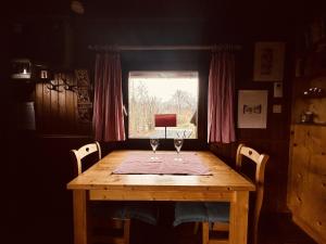 een houten tafel met twee wijnglazen erop bij Rustic Chalet ultimate relaxation in the forest in Sourbrodt