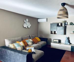 a living room with a gray couch with colorful pillows at Quinta do Pica-Pau Amarelo in Grândola