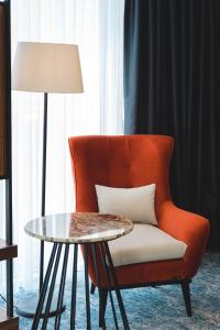 a orange chair with a table and a lamp at Bristol Hotel Podgorica in Podgorica