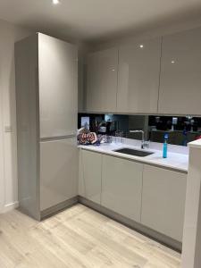 uma cozinha com armários brancos e um lavatório em Beautiful 3 Bedroom Duplex Apartment with Balcony em North Woolwich